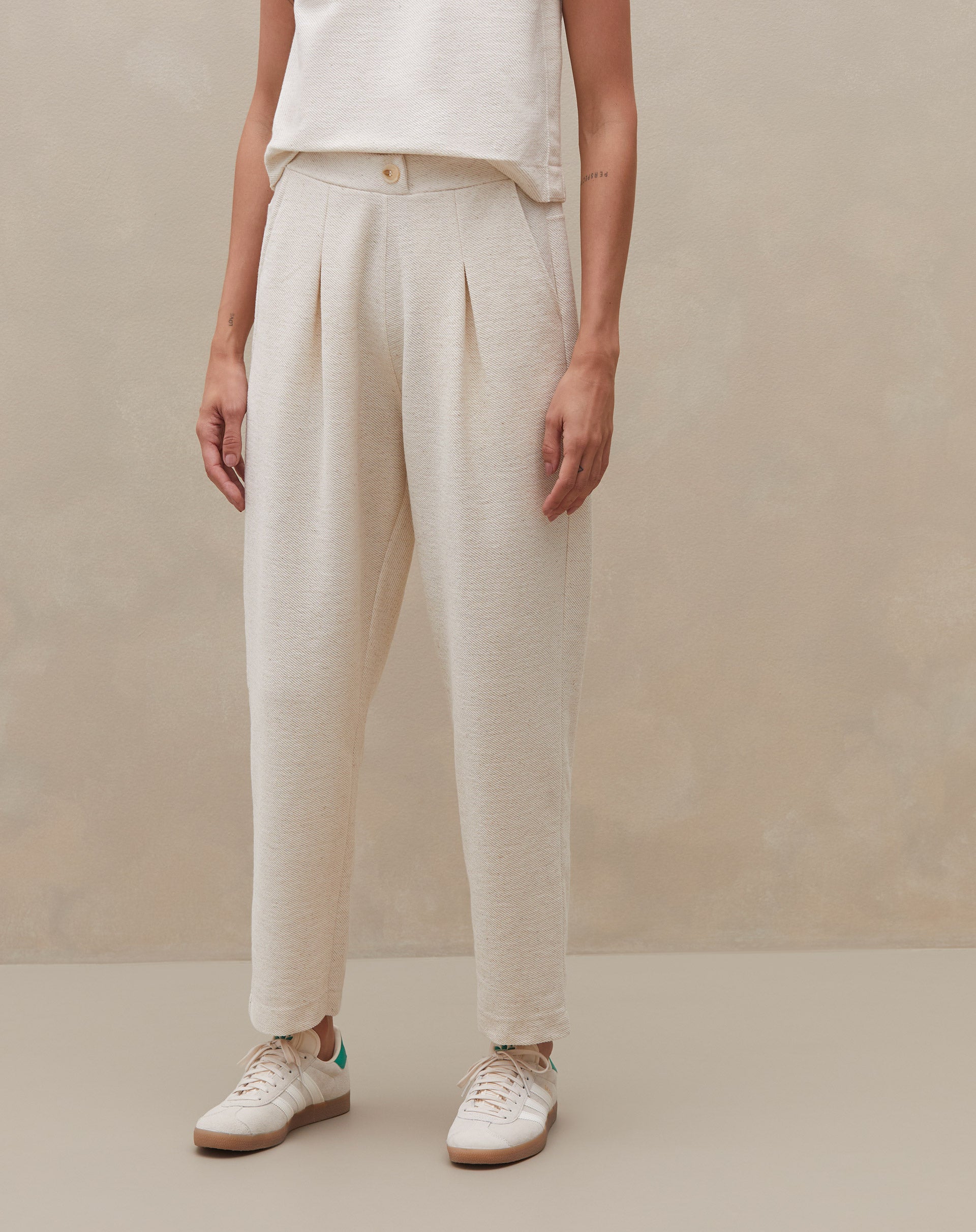 Modelo mostrando detalhes da calça de cintura alta, vista lateral.