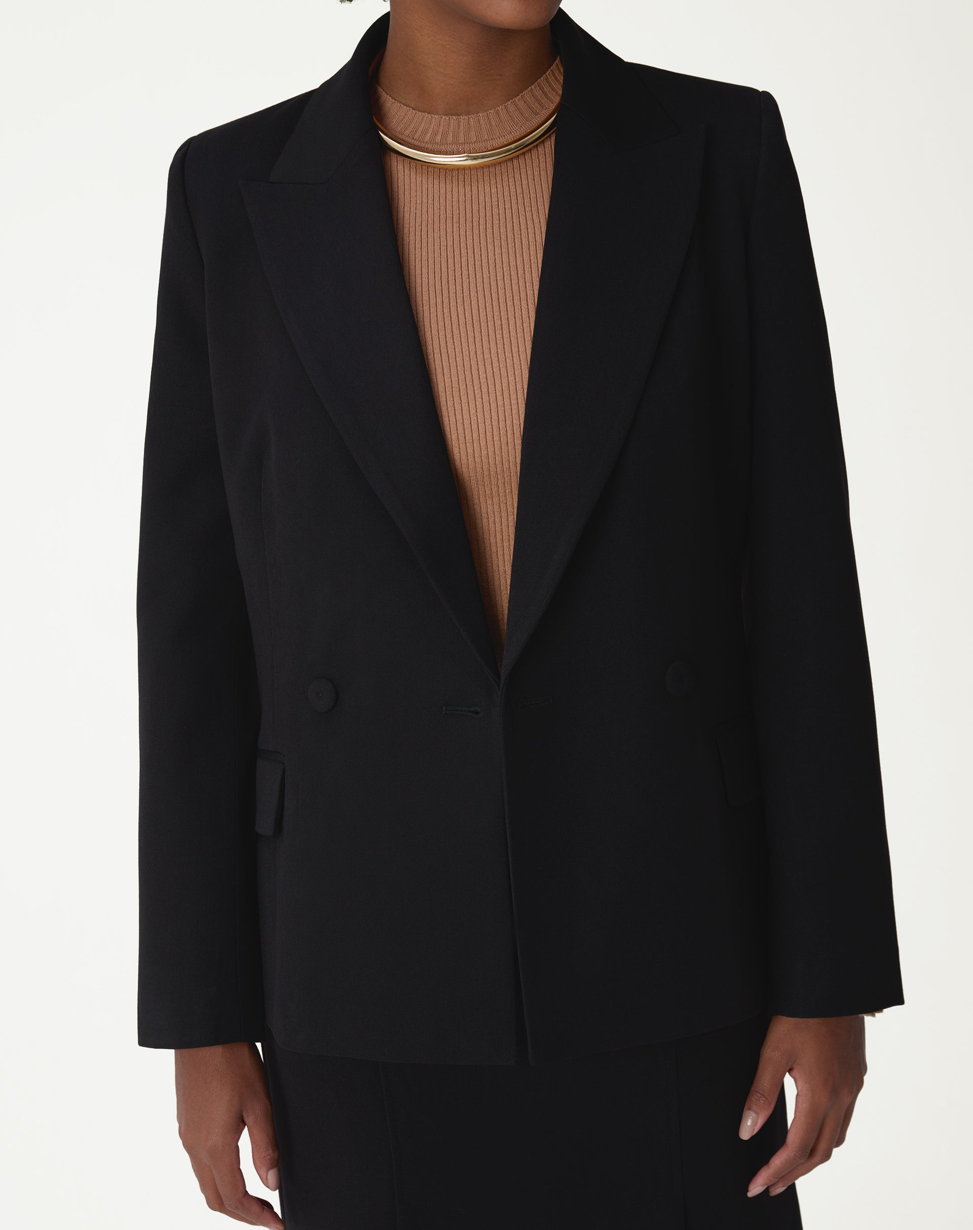 Blazer preto slim abotoamento duplo em modelo, vista frontal até o busto com lapela de ponta e colar dourado em destaque