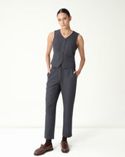 Modelo usa conjunto feminino com colete slim cinza e calça alfaiataria em fundo branco.