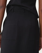 Detalhe traseiro da saia preta com bolsos aplicados quadrados e costura central.