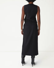 Vista traseira da modelo usando saia midi preta alfaiataria mostrando comprimento e caimento.