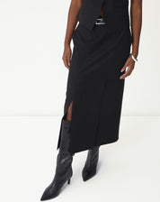 Detalhe da fenda lateral da saia midi preta mostrando abertura, caimento e bota cano alto.