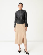 Modelo vestindo saia midi alfaiataria bege com fenda lateral e jaqueta preta, cós médio e comprimento midi, look elegante para escritório