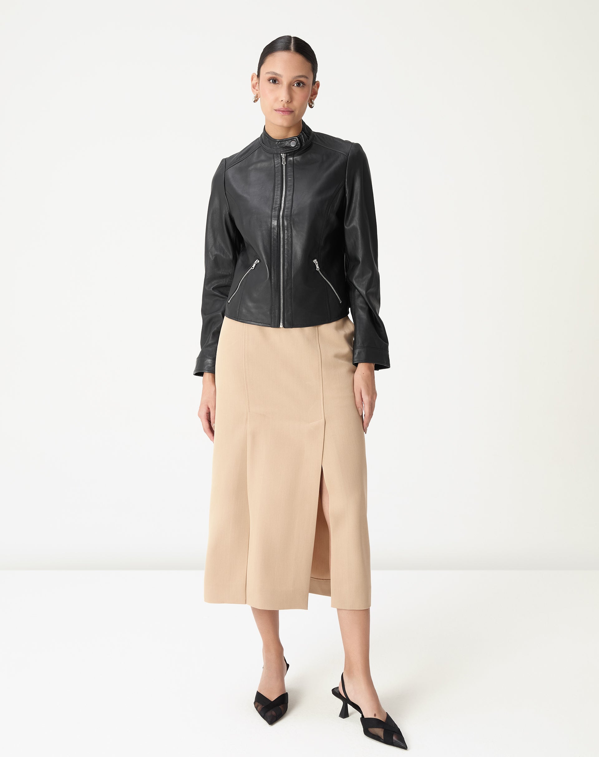 Modelo vestindo saia midi alfaiataria bege com fenda lateral e jaqueta preta, cós médio e comprimento midi, look elegante para escritório