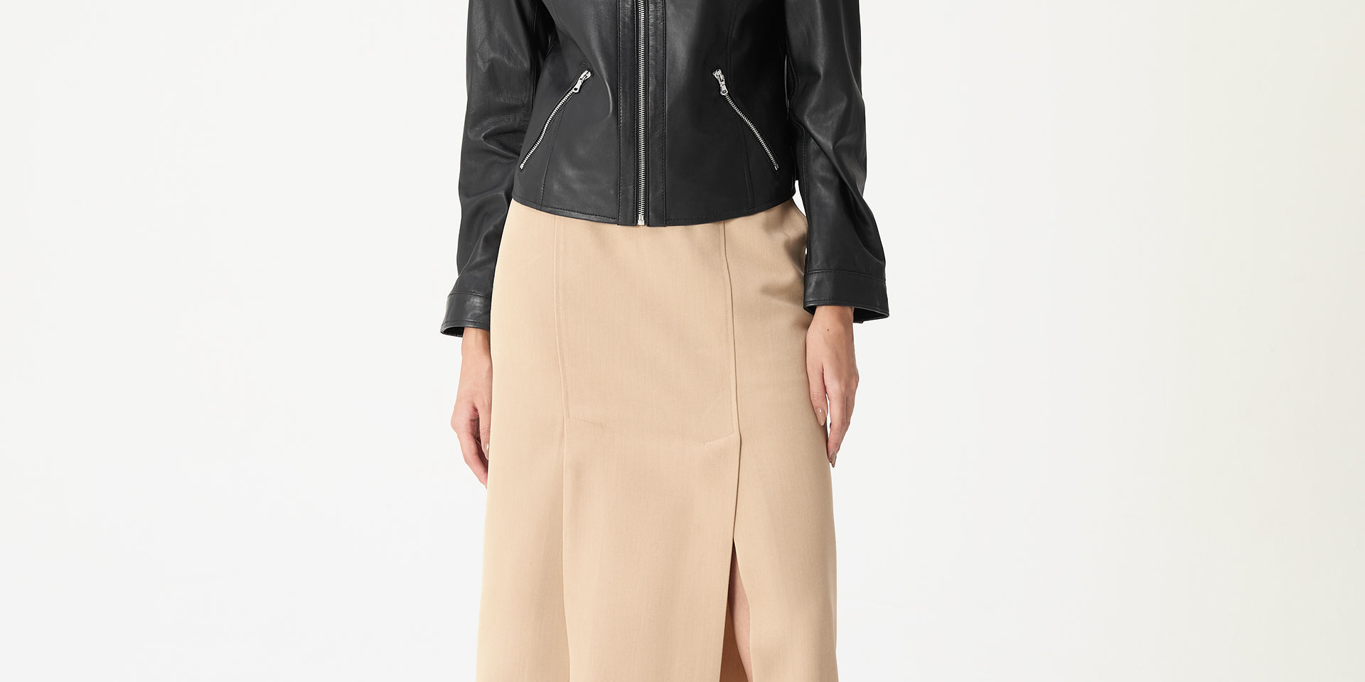 Modelo vestindo saia midi alfaiataria bege com fenda lateral e jaqueta preta, cós médio e comprimento midi, look elegante para escritório