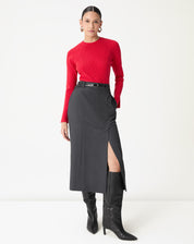 Saia midi alfaiataria cinza com fenda lateral vista frontal em modelo usando suéter vermelho e botas pretas, destacando corte reto e cós médio.