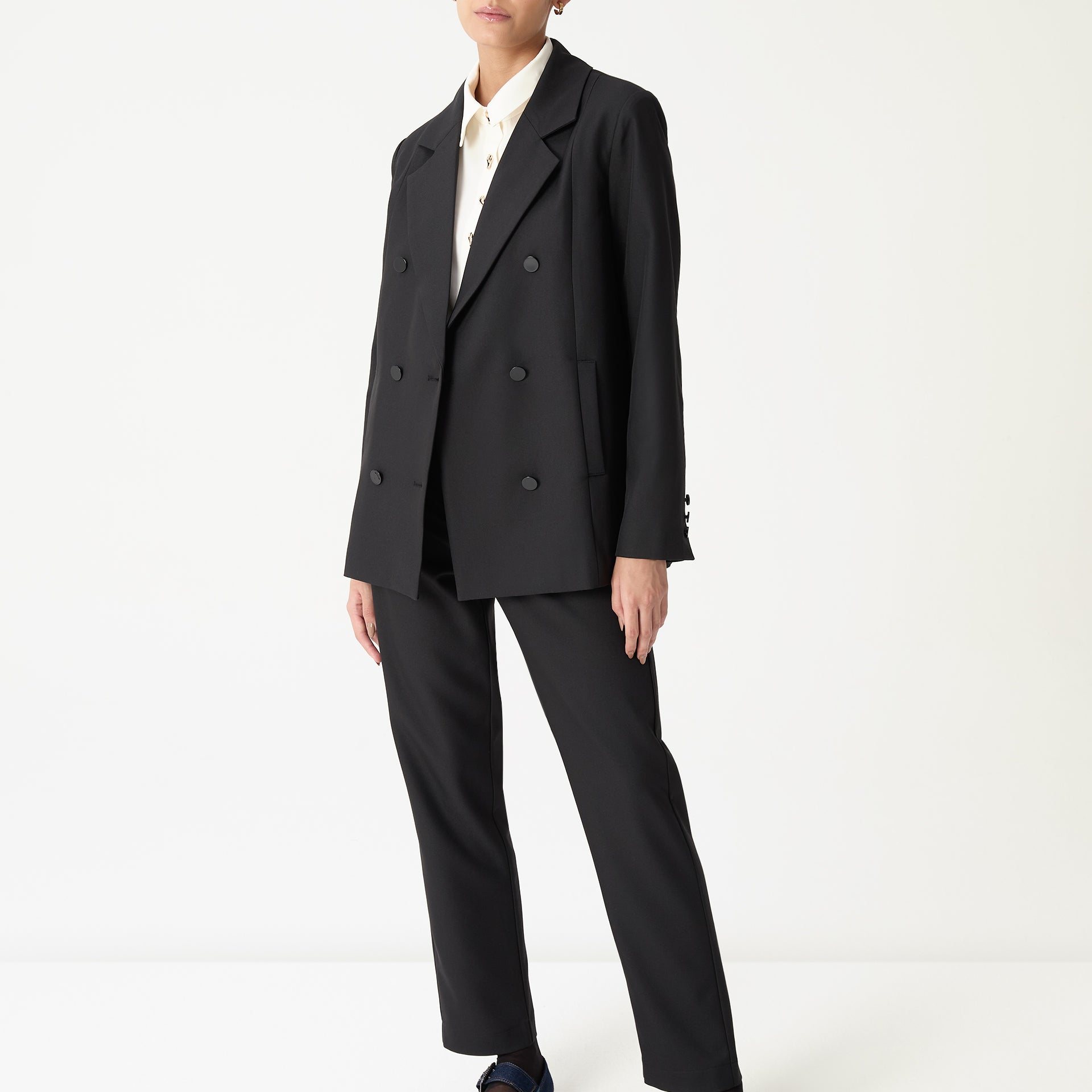 Blazer oversized preto longo em look completo visto de frente com calça reta preta e mocassim azul-marinho, imagem frontal full body.
