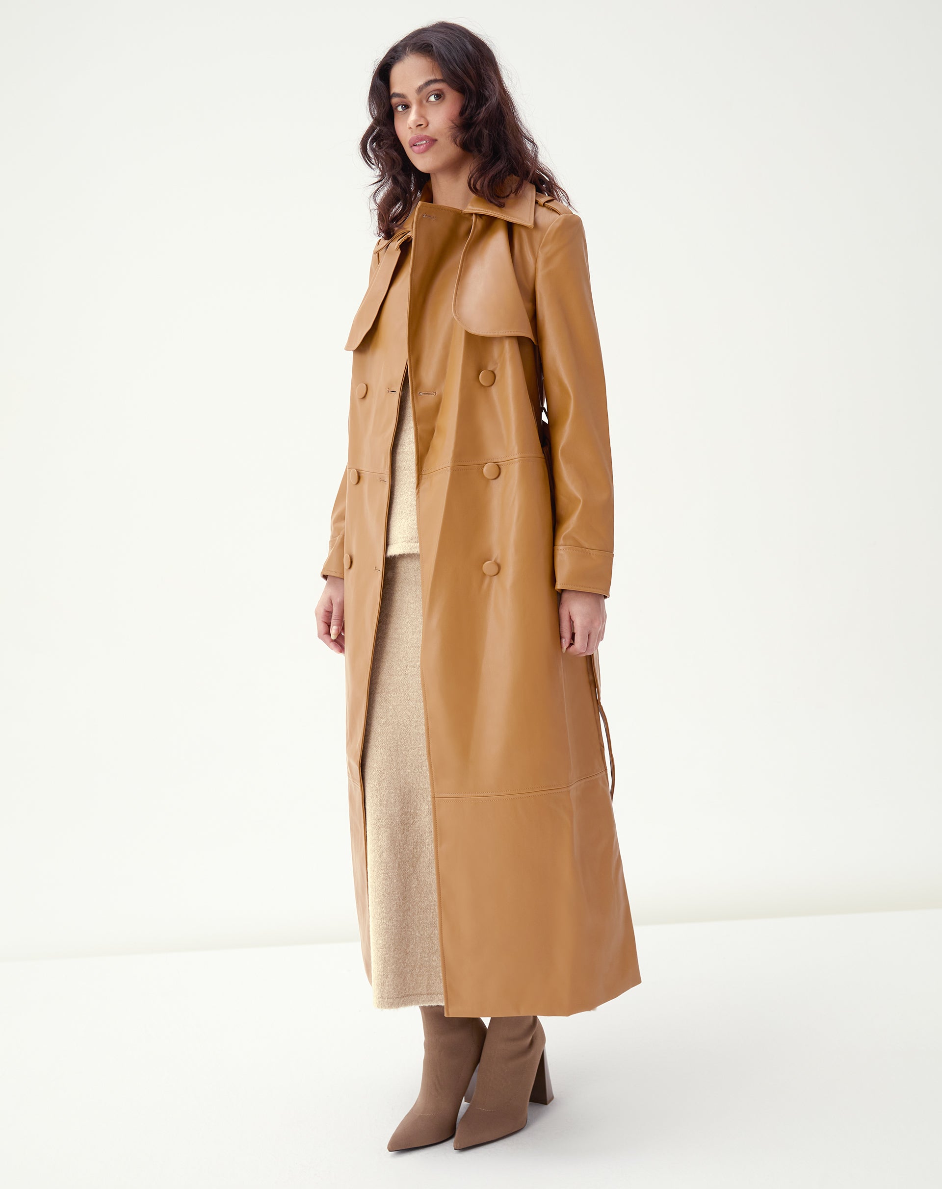 Modelo usando trench coat PU caramelo longo vista frontal com abotoamento duplo e cinto