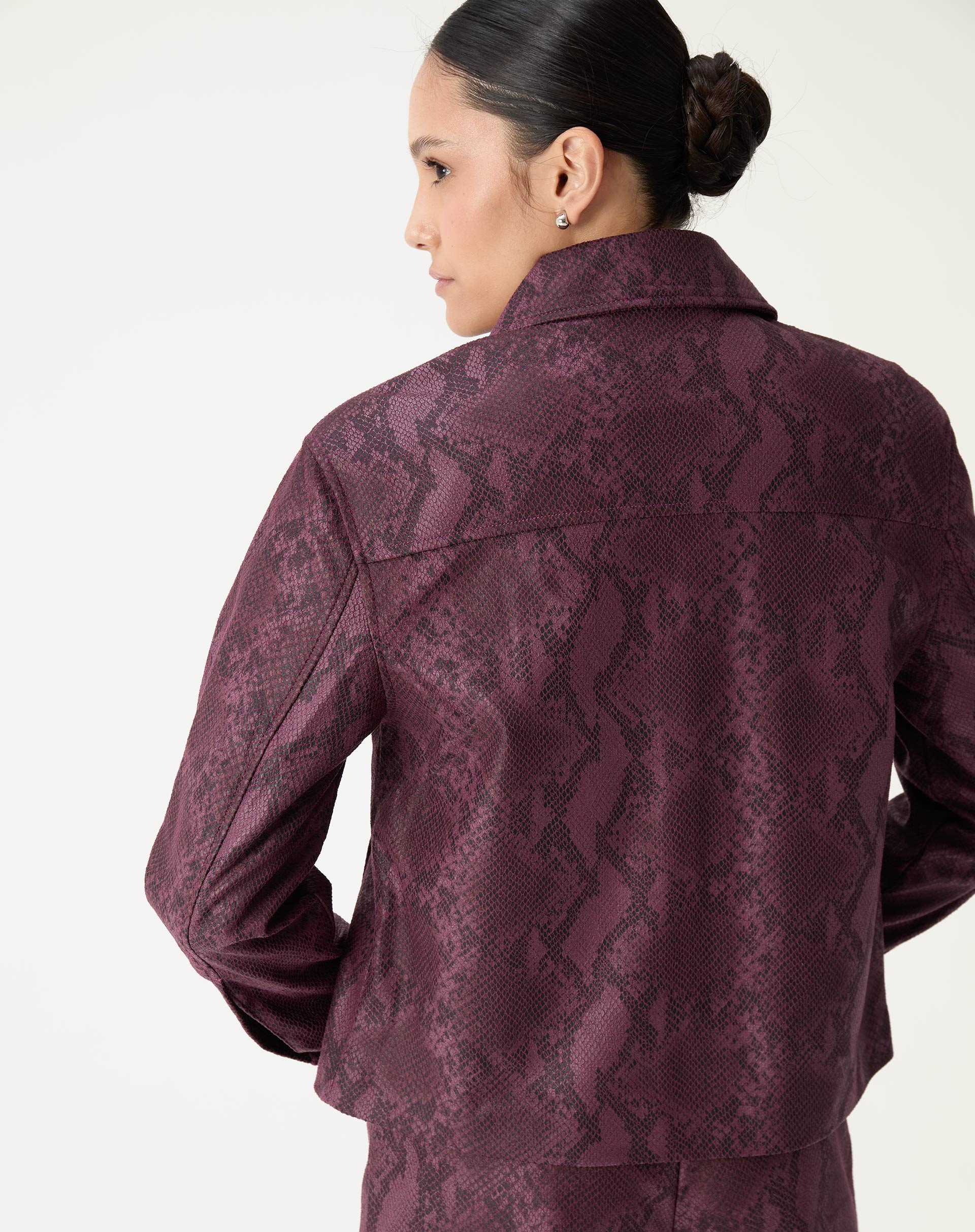 Detalhe do colarinho clássico da jaqueta vinho com padronagem snake print e botões frontais.