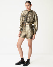Look completo com jaqueta bomber dourada e shorts coordenados, styling urbano com mocassim preto