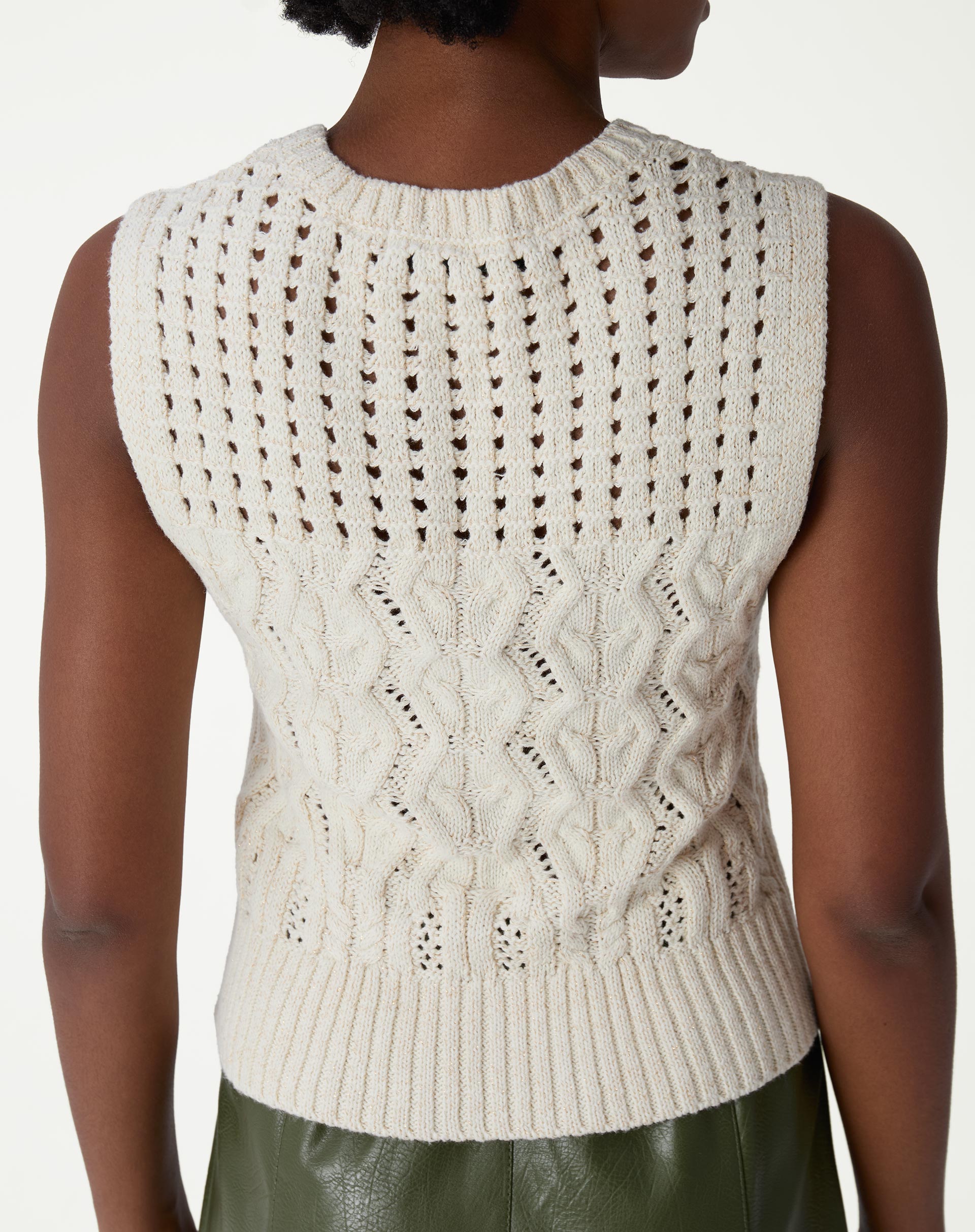 Conjunto completo com regata de tricô bege, saia midi verde e tênis branco, estilo casual-chique em ambiente de estúdio.