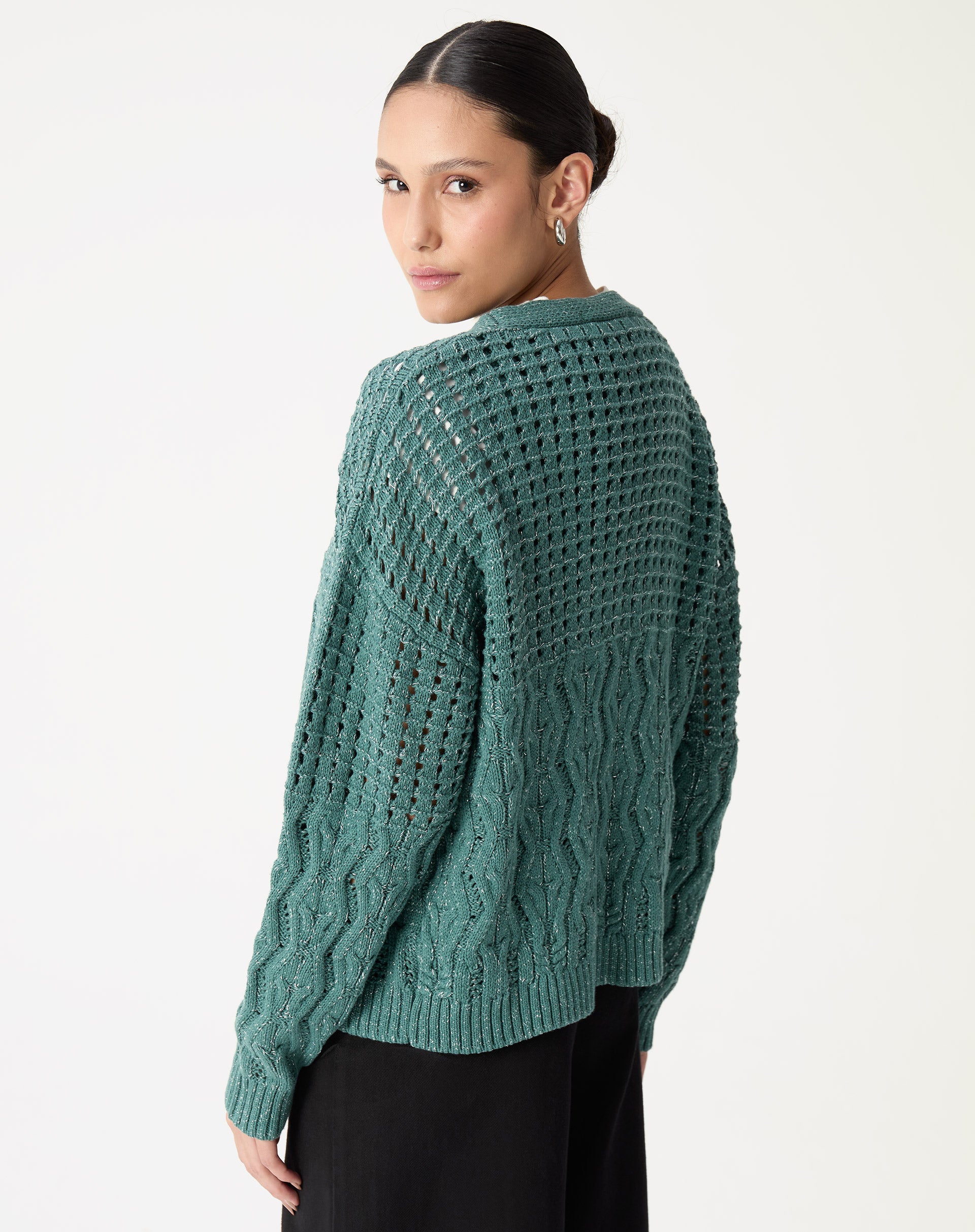 Detalhe da manga com punho canelado do cardigan de tricô verde mostrando acabamento e ponto trançado.