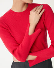 Detalhe do tecido canelado e pequena abertura no punho do suéter vermelho em close.