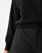Close do tecido em cashmere preto e acabamento da barra canelada, textura macia do tricot