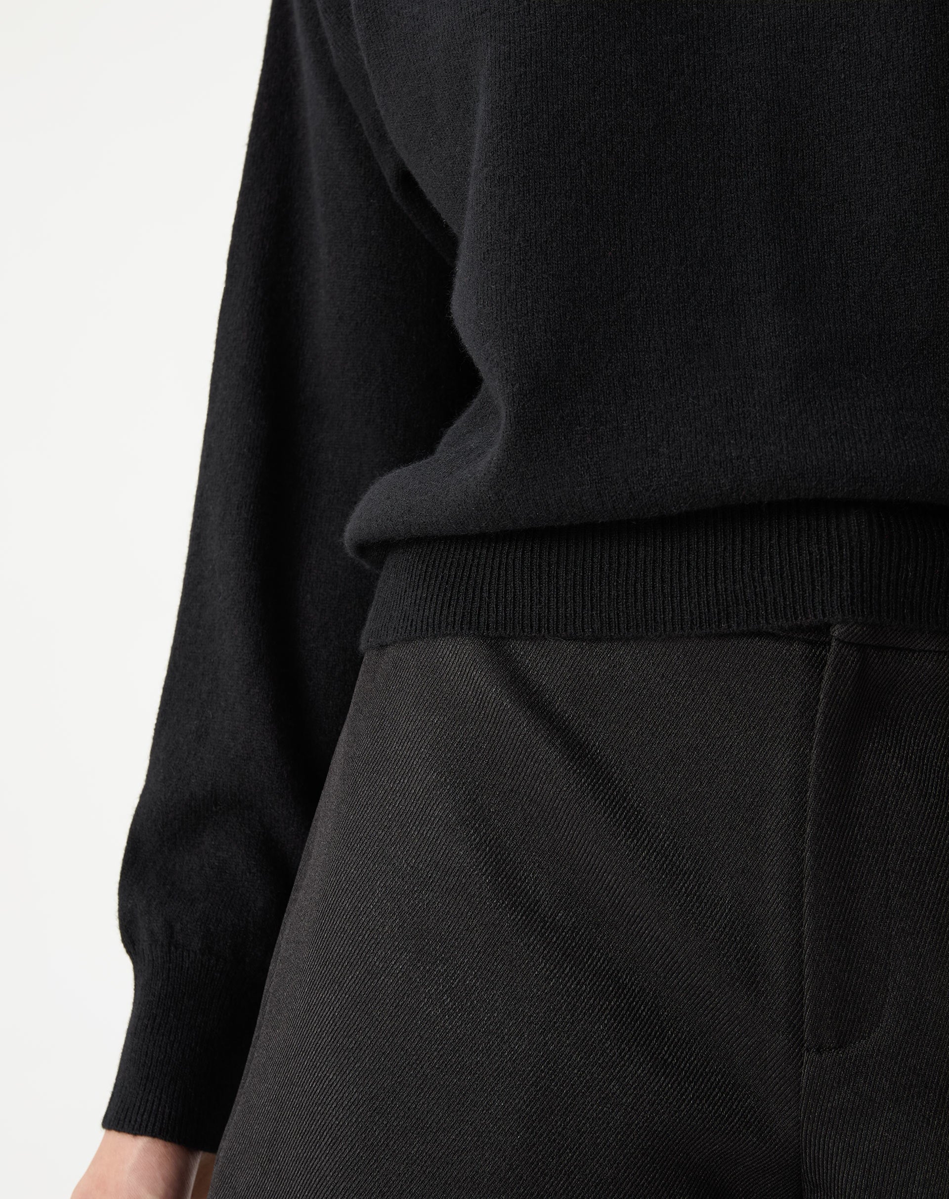Close do tecido em cashmere preto e acabamento da barra canelada, textura macia do tricot