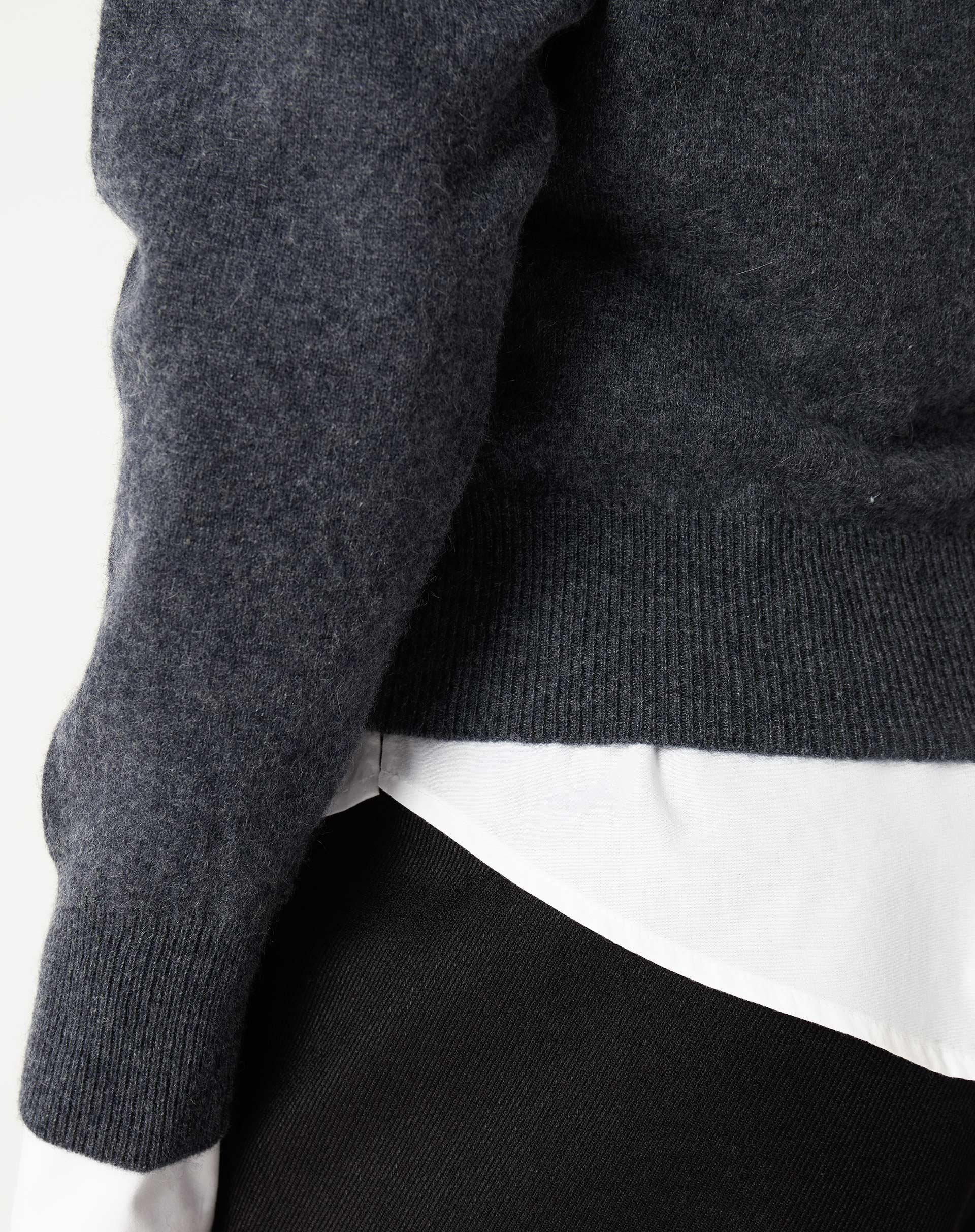 Imagem detalhada do decote em V do suéter cashmere cinza escuro para sobreposição com camisa branca