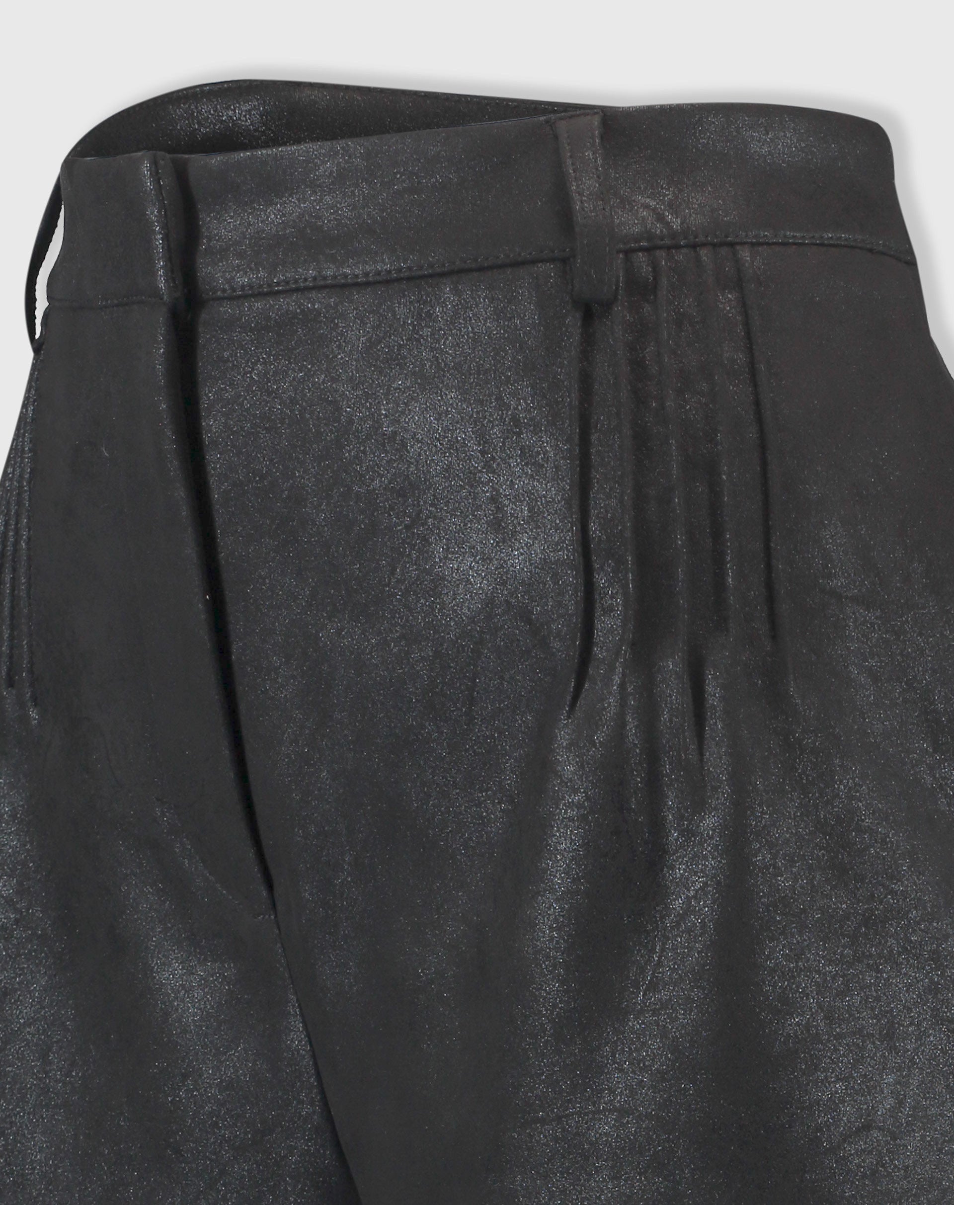 Detalhe em close do tecido suedine com acabamento metalizado do shorts preto, evidenciando textura e costuras
