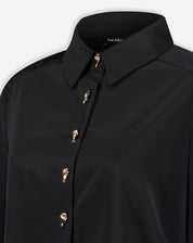 Close-up do colarinho pontudo e parte superior da camisa preta mostrando o acabamento da gola e o primeiro botão dourado