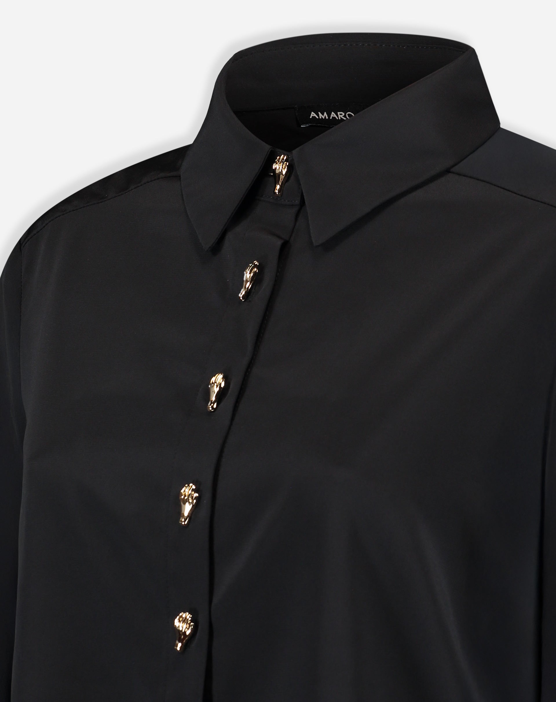 Close-up do colarinho pontudo e parte superior da camisa preta mostrando o acabamento da gola e o primeiro botão dourado