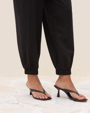 Detalhe do bolso lateral embutido da calça jogger em tecido liso preto, corte limpo e função prática