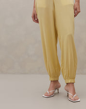 Detalhe das pernas da Calça Jogger Aladim mostrando punhos elásticos e caimento fluido em tom manteiga