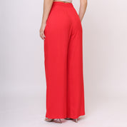 Calça pantalona vermelha vista lateral com modelo usando a mão no bolso lateral, perna ampla e detalhe do caimento