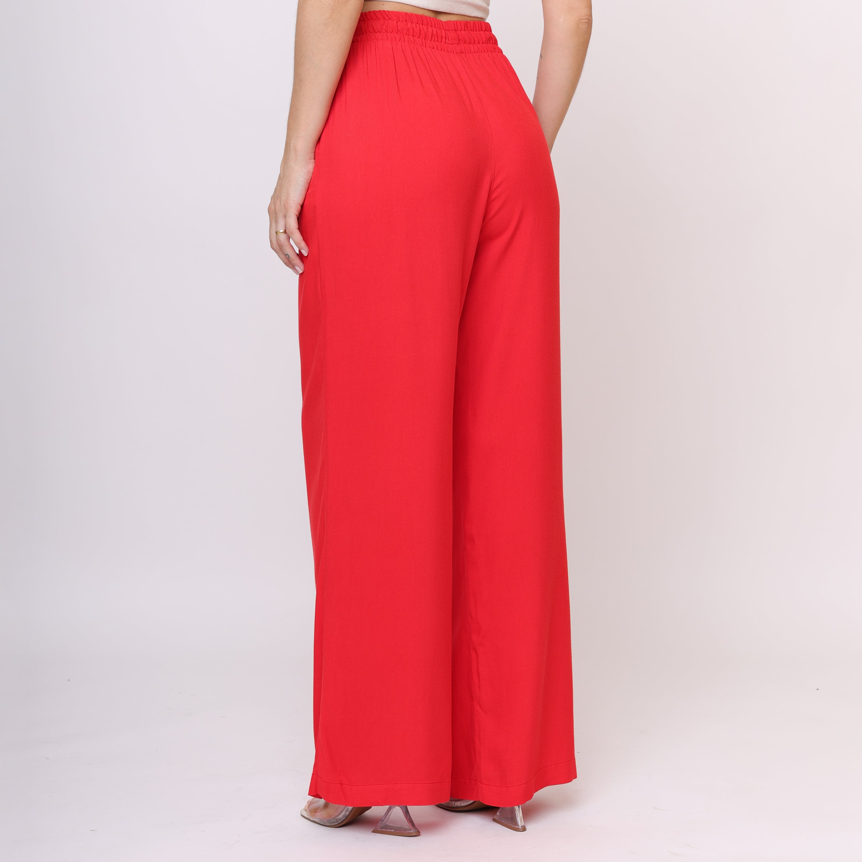 Calça pantalona vermelha vista lateral com modelo usando a mão no bolso lateral, perna ampla e detalhe do caimento